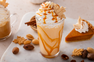 Copo de café gelado com espuma cremosa ao lado de garrafas de bases saborizantes.